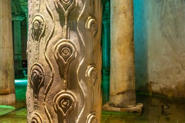 Ancient stone columns with intricate carvings in historic underground structure.