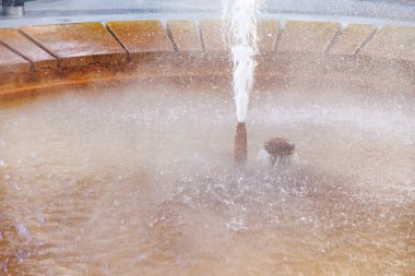 Circular water fountain with mist and stone surroundings, natural geyser.