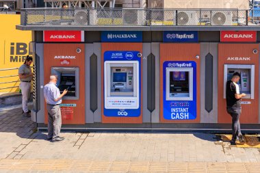 Men using outdoor atms from various banks on a sunny day. August 12, 2025 Istanbul Turkey.
