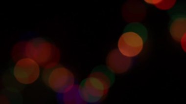 Yeni Yıl 'ın çok renkli çelenklerinin odağından çıkarılmış soyut arka planı. Bokeh ve bardaktaki yağmur damlaları. Gecenin şenlikli ışıkları.