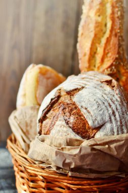 Hasır sepetteki fırın ürünleri. Yuvarlak ev yapımı ekmek, tohumlu uzun somun, mayasız vejetaryen ekmeği..