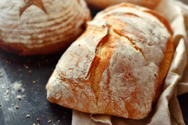Hasır sepetteki fırın ürünleri. Yuvarlak ev yapımı ekmek, tohumlu uzun somun, mayasız vejetaryen ekmeği..