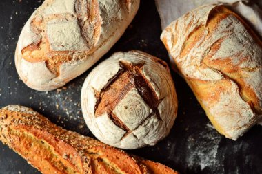Fırın ürünleri. Koyu arka planda çıtır çıtır, güzel bir ekmek. Karabuğday, mayasız, keten ve ayçiçeği tohumlu buğday ekmeği. Üst görünüm, metin için yer.