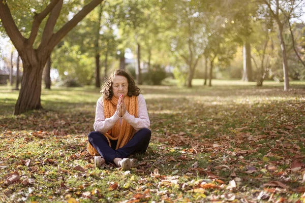 Kafkasyalı yaşlı kadın dışarıda meditasyon yapıyor. Doğadaki emekli kişi. Metin için boşluk.