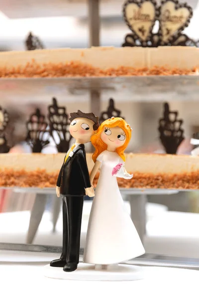Detail of bride and groom figures next to wedding cake. Concept of marriage bond.