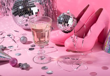 Pembe arka planda gümüş aynalı disko topu olan bir kadeh şampanya. Yeni yıl parti kompozisyonu