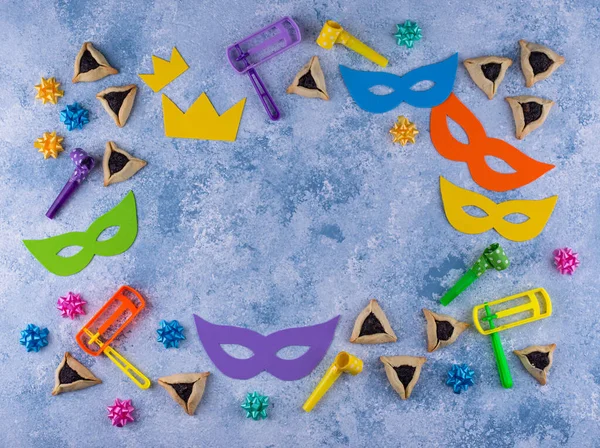 Jewish holiday Purim with carnival mask, traditional cookies Hamantaschen and rattle