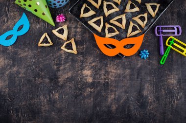 Jewish holiday Purim with carnival mask, traditional cookies Hamantaschen and rattle