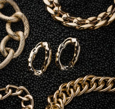 Golden chains earrings on black background. Jewelry photography concept