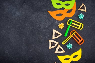 Jewish holiday Purim with carnival mask, traditional cookies Hamantaschen and rattle