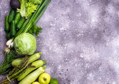 Çeşitli yeşil sebzeler ve meyveler. Kuşkonmaz, salatalık, lahana, kabak, elma, avokado ve soğan.