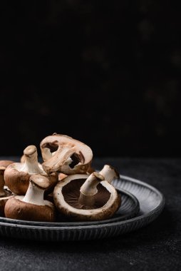 Siyah arka planda pişmemiş şampiyon mantarları.