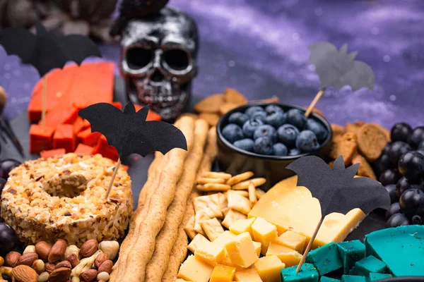 Cheese plate with berries, grapes, nuts and snacks. Halloween food.