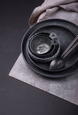 Demir sofra takımı, tabaklar, kaseler ve fincanlar gri arkaplanda.