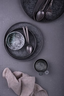 Demir sofra takımı, tabaklar, kaseler ve fincanlar gri arkaplanda.