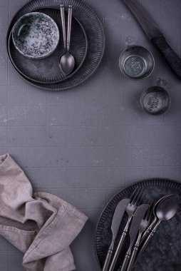 Demir sofra takımı, tabaklar, kaseler ve fincanlar gri arkaplanda.