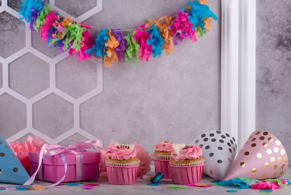 Birthday party concept with cupcake, confetti and garland