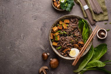 Soba eriştesi, tofu ve mantarlı koyu arkaplan.