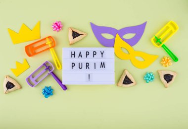 Jewish holiday Purim with carnival mask, traditional cookies Hamantaschen and rattle