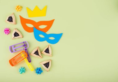 Jewish holiday Purim with carnival mask, traditional cookies Hamantaschen and rattle