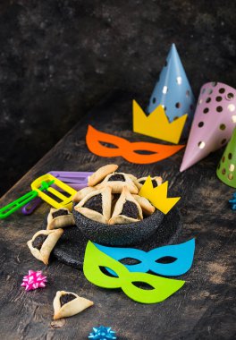 Jewish holiday Purim with carnival mask, traditional cookies Hamantaschen and rattle