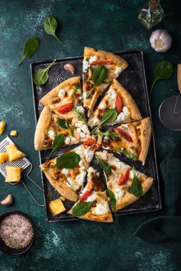 Italian home made pizza with feta cheese, tomato and basil