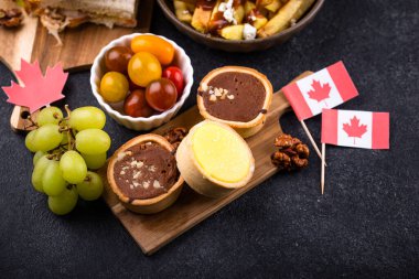 Kanada Günü geleneksel gıda konsepti. Poutine, tereyağlı tart, sandviç, akçaağaç şuruplu Kanada gözlemesi.