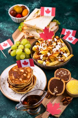 Kanada Günü geleneksel gıda konsepti. Poutine, tereyağlı tart, sandviç, akçaağaç şuruplu Kanada gözlemesi.