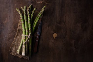 Koyu arkaplanda taze yeşil kuşkonmaz. Karanlık ruh hali tarzı