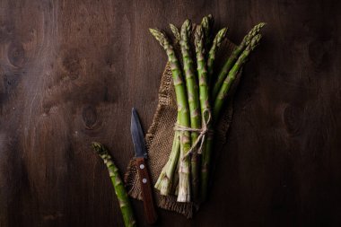 Koyu arkaplanda taze yeşil kuşkonmaz. Karanlık ruh hali tarzı