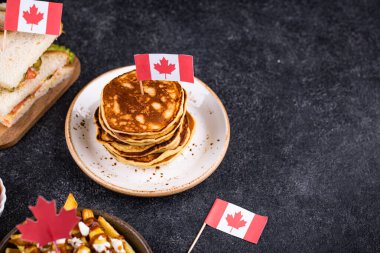 Kanada Günü geleneksel gıda konsepti. Poutine, tereyağlı tart, sandviç, akçaağaç şuruplu Kanada gözlemesi.