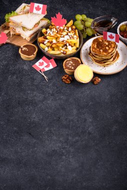 Kanada Günü geleneksel gıda konsepti. Poutine, tereyağlı tart, sandviç, akçaağaç şuruplu Kanada gözlemesi.