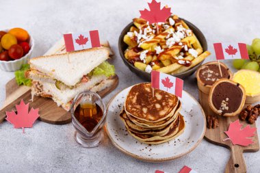 Kanada Günü geleneksel gıda konsepti. Poutine, tereyağlı tart, sandviç, akçaağaç şuruplu Kanada gözlemesi.