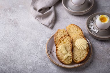 Haşlanmış yumurta, kabuk şeklinde ekmek ve tereyağı ile kahvaltı.