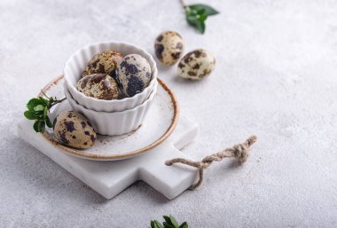 Arka planda çiğ bıldırcın yumurtası olan bir kase.