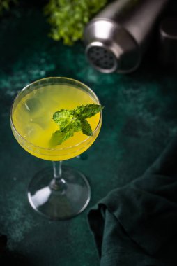 Yeşil zemin üzerinde nane olan tropik sarı limon kokteyli.