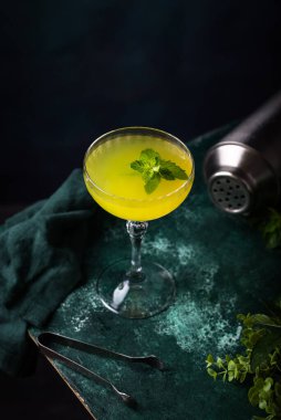 Yeşil zemin üzerinde nane olan tropik sarı limon kokteyli.