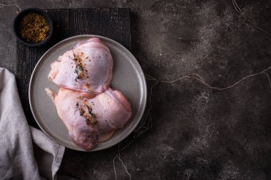 Koyu mutfak masasında çiğ tavuk butları.