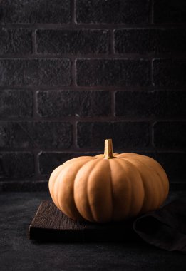 Koyu arka planda çiğ balkabağı, karanlık ruh hali tarzı.