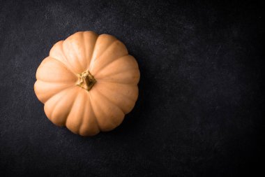 Koyu arka planda çiğ balkabağı, karanlık ruh hali tarzı.