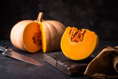 Koyu arka planda çiğ balkabağı, karanlık ruh hali tarzı.