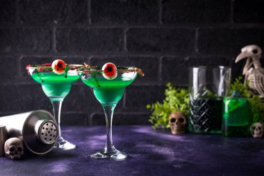 Yeşil cadılar bayramı kokteylleri, koyu mor arka planda gözbebekleri olan.