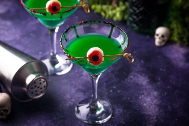 Mor arka planda yüzen gözleri olan ürkütücü yeşil kokteyller, cadılar bayramı teması