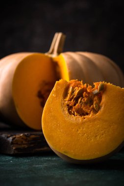 Koyu arka planda çiğ balkabağı, karanlık ruh hali tarzı.