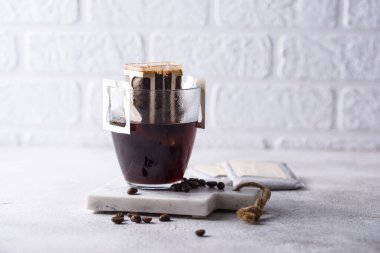 Koyu, taze demlenmiş kahveyle dolu cam bir sürahi beyaz tuğladan bir arka plana karşı..