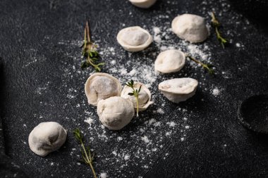 Taze yapılmış hamur tatlısı, un tozuyla kaplanmış karanlık bir yüzeyde dinleniyor..