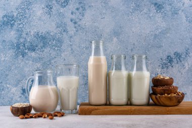 Süt şişeleri, sürahi ve hamur işleri de dahil olmak üzere çeşitli süt ürünlerini gösteren tahta bir tahta tahta. Arka plan serin mavi bir renktir..