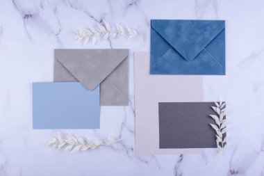 Beyaz mermer arka planda çiçek dalları olan zarflar ve kağıtlar..