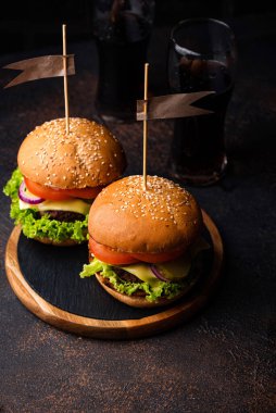 Koyu arkaplanda domatesli hamburger ve çizburger.