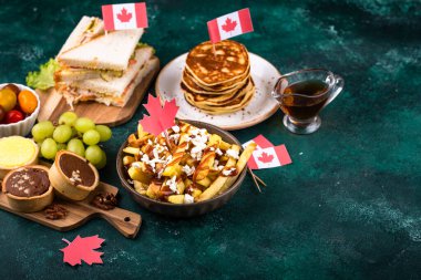 Kanada Günü geleneksel gıda konsepti. Poutine, tereyağlı tart, sandviç, akçaağaç şuruplu Kanada gözlemesi.